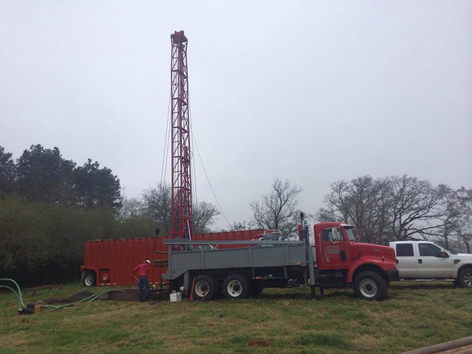 Holly Water Wells rig and service truck on a rural East Texas property